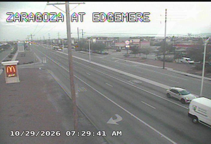 Light traffic on a multi-lane road with a white SUV and a white van moving in the same direction; a McDonald's sign is visible on the left side of the road.