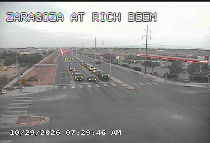 Multiple vehicles are moving through an intersection under overcast skies, with no visible traffic incidents or road work.