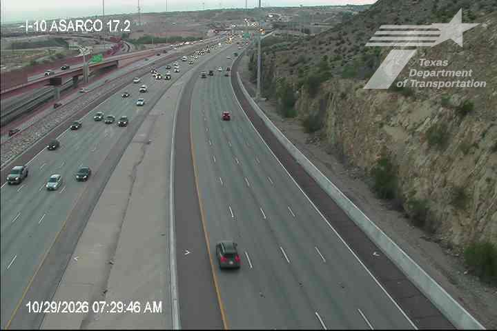 Multi-lane highway with moderate traffic flow, vehicles moving in both directions under clear skies, no visible incidents or road work.
