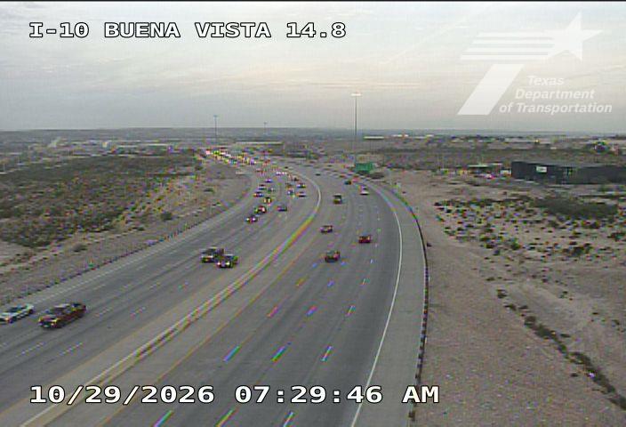 Light traffic flows along a multi-lane highway with vehicles moving in both directions; sparse desert landscape surrounds the road with no visible work zones or incidents.