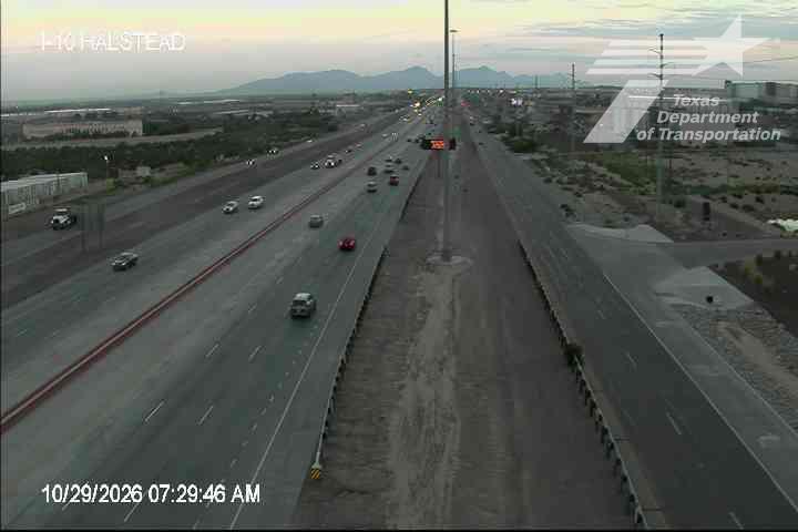 Light traffic flows along a multi-lane highway with distant mountains under a clear sky, no visible work zones or incidents.