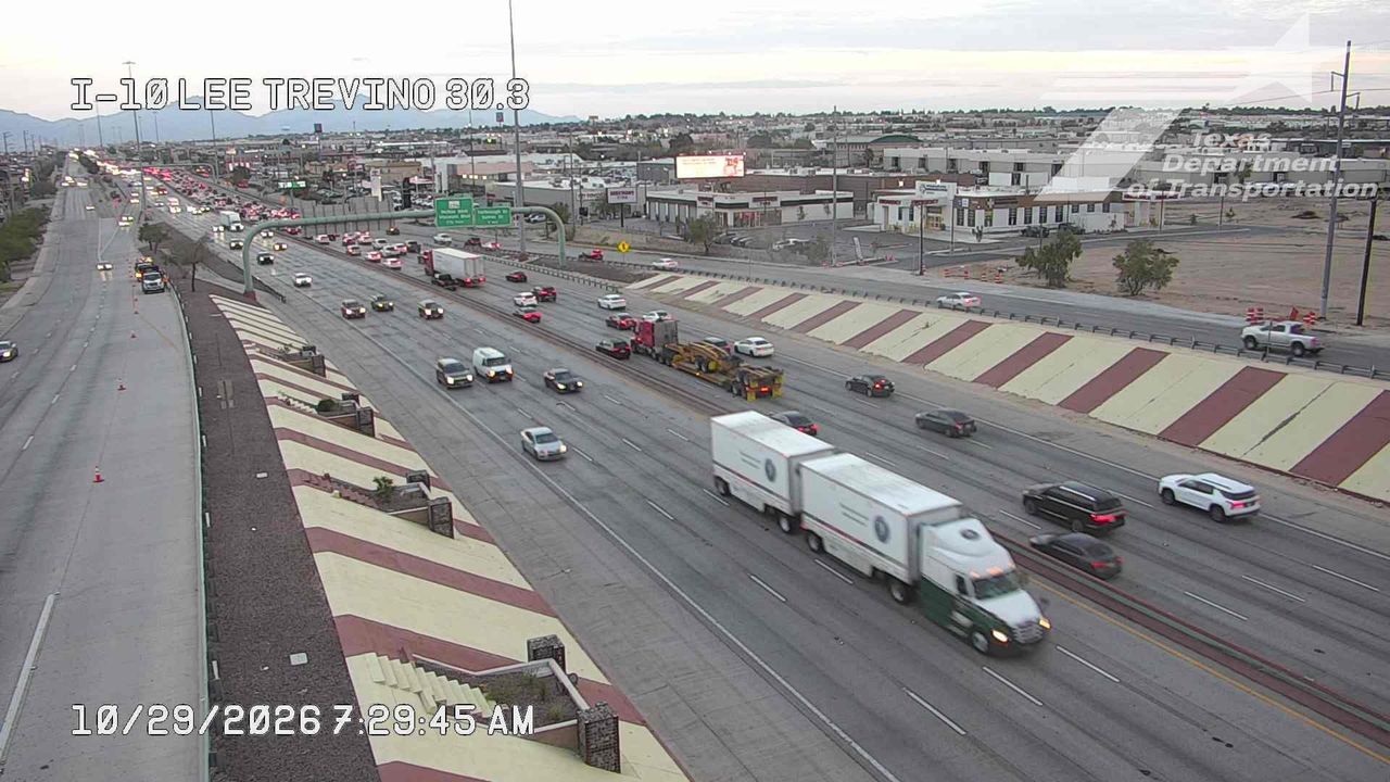 Multi-lane highway with moderate traffic flow, featuring semi-trucks and passenger vehicles moving in both directions; no visible incidents or road work zones.
