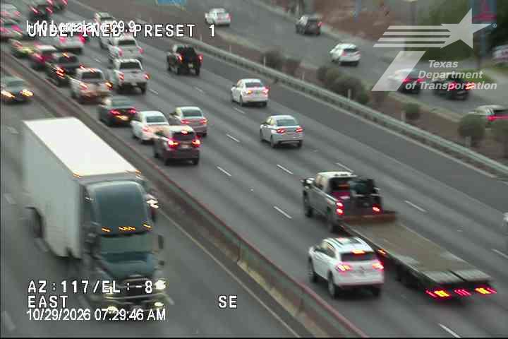 Multi-lane highway with moderate traffic flow, including a large semi-truck and a flatbed tow truck transporting a vehicle, under clear weather conditions.