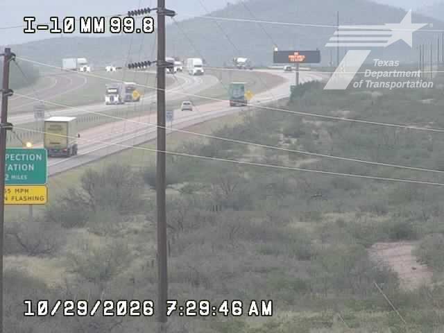 Multi-lane highway with moderate traffic flow, including several semi-trucks and a few passenger vehicles, under overcast skies with reduced visibility due to haze or fog.