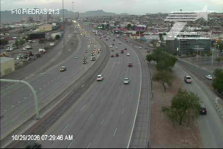 Multi-lane highway with moderate traffic flow, vehicles moving in both directions, no visible incidents or road work, clear weather with distant mountains in background.
