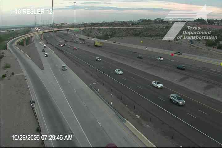 Multi-lane highway with moderate traffic flow under clear skies, featuring vehicles moving in both directions with no visible incidents or road work.