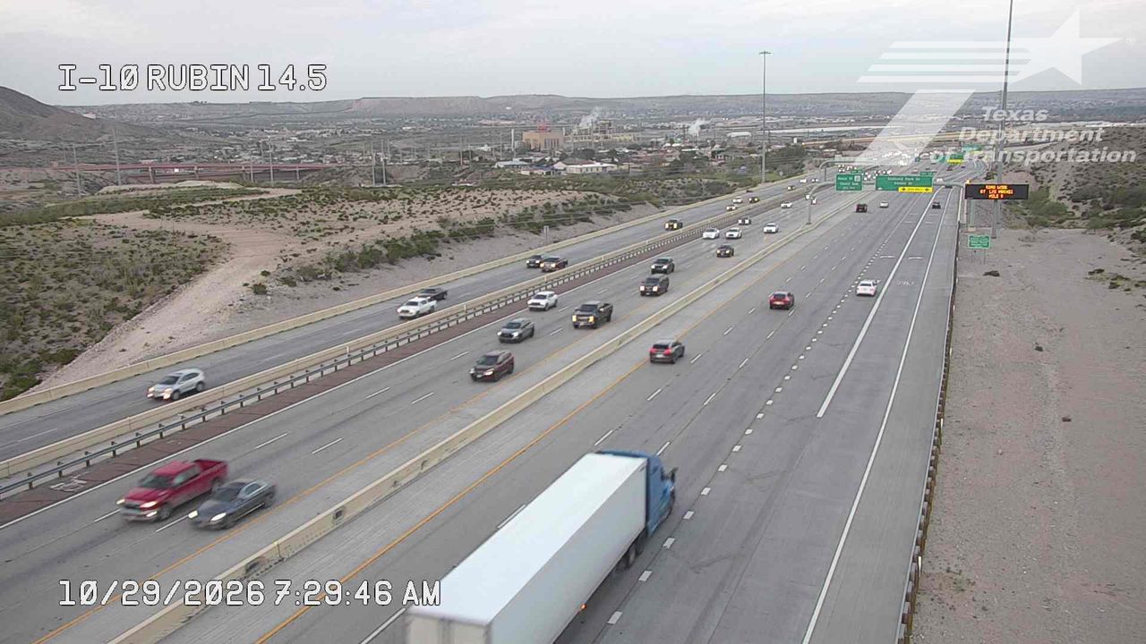 Multi-lane highway with moderate traffic flow, including a large semi-truck and several passenger vehicles moving freely under overcast skies.