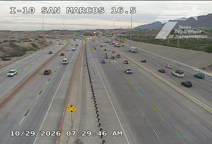 Multi-lane highway with moderate traffic flowing in both directions, no visible incidents or road work, under clear skies with distant mountains in background.