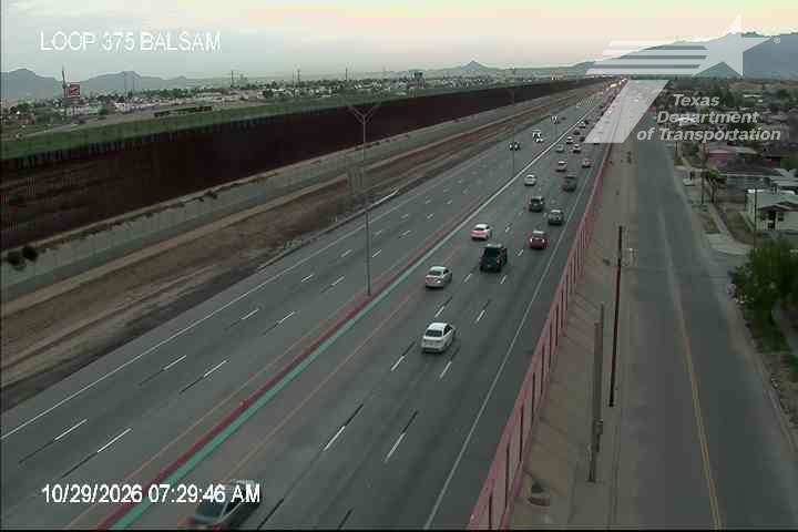 Multi-lane highway with moderate traffic flow, vehicles moving steadily in both directions under clear skies.