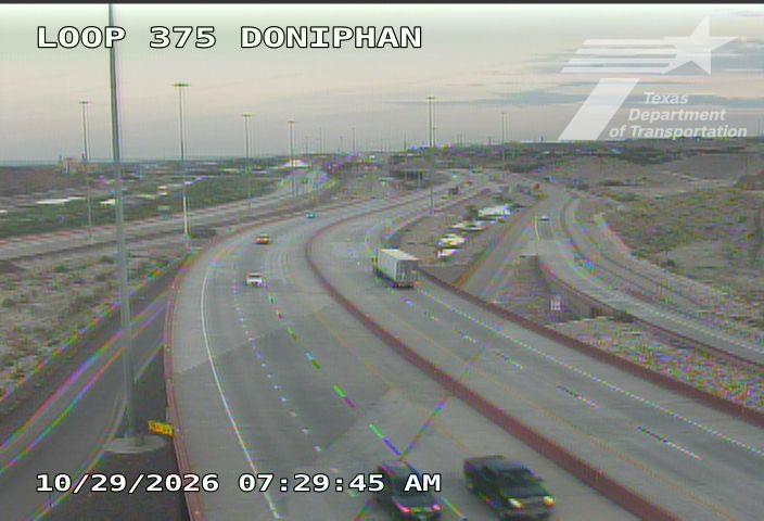 Light traffic flows on a multi-lane highway curve with a semi-truck and several cars moving steadily; no visible incidents or road work.