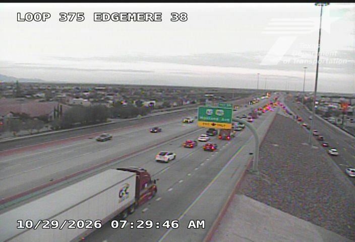 Multi-lane highway with moderate traffic flow, including a large semi-truck and several cars, under overcast skies with no visible incidents or road work.