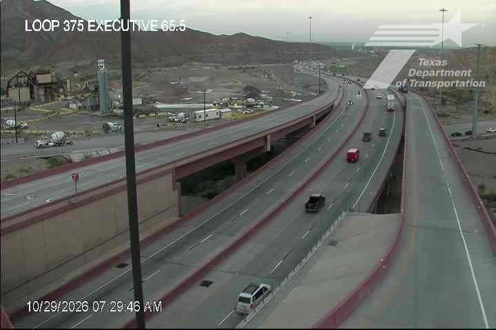 Multi-level highway with moderate traffic flow under overpasses, featuring trucks and passenger vehicles moving freely with no visible incidents or road work.