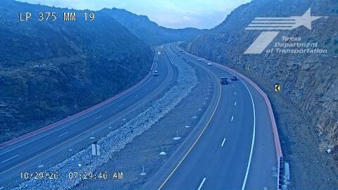 A multi-lane highway winds through mountainous terrain with light traffic moving in both directions; no visible work zones or incidents.