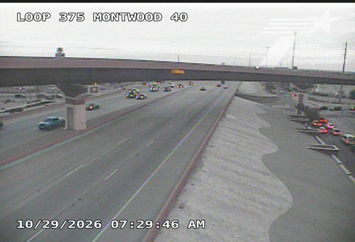Multi-lane highway with moderate traffic flowing under an overpass; vehicles moving steadily in both directions with no visible incidents or road work.