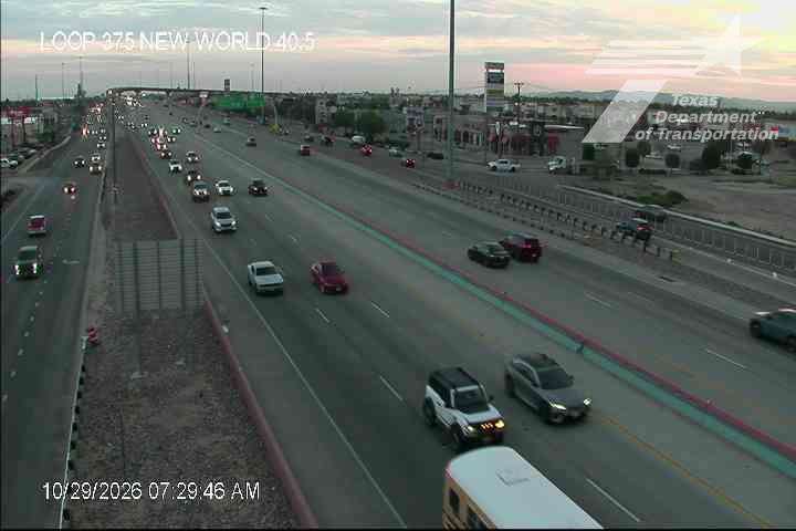 Multi-lane highway with moderate traffic flow during early morning hours, featuring a mix of passenger cars, SUVs, and a school bus, with no visible incidents or road work zones.