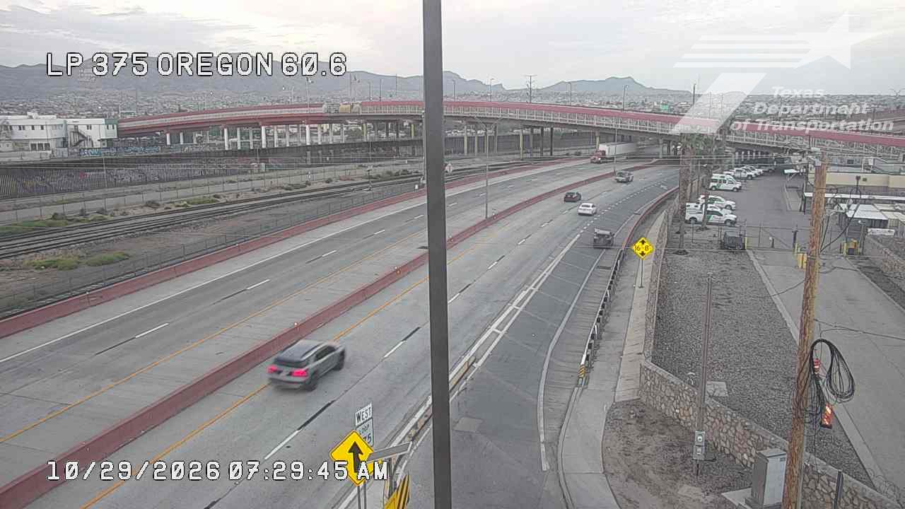 A multi-lane highway with light traffic flows under an overpass, with a few vehicles moving at moderate speed and no visible incidents or road work.