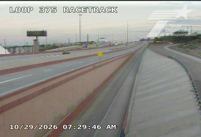 A multi-lane highway with light traffic moving in both directions, separated by a concrete barrier; no visible incidents or road work.