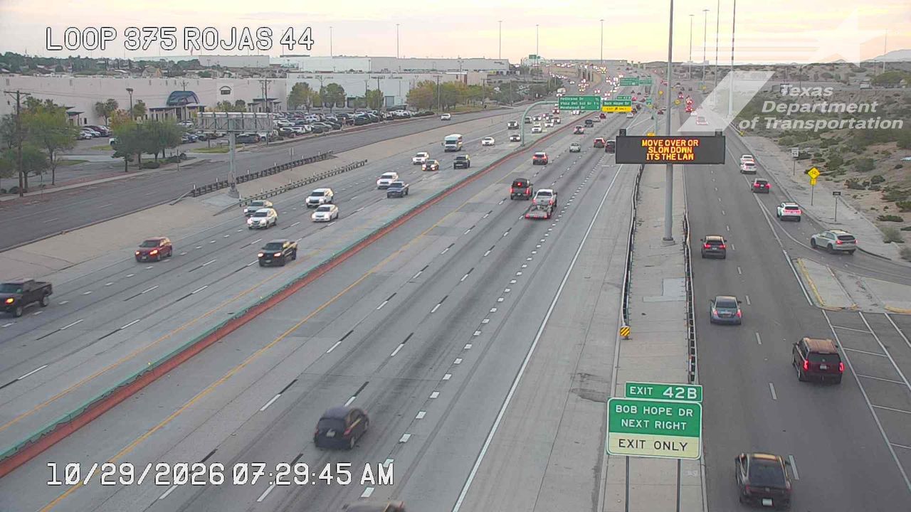 Multi-lane highway with moderate traffic flow, vehicles moving in both directions under clear skies.