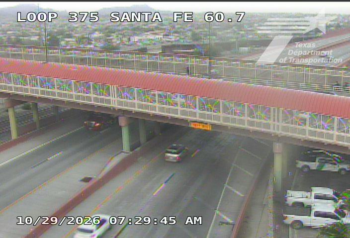 A multi-lane highway under an overpass with light traffic moving in both directions; vehicles include sedans and trucks, with no visible incidents or road work.