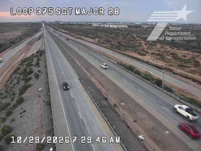 Multi-lane highway with moderate traffic flow, vehicles moving freely in both directions, no visible incidents or road work, dry desert landscape on either side, clear weather conditions.