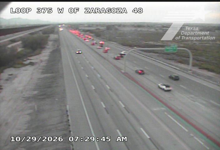 Traffic is slow on a multi-lane highway with a line of vehicles and construction equipment visible in the distance, indicating an active work zone.