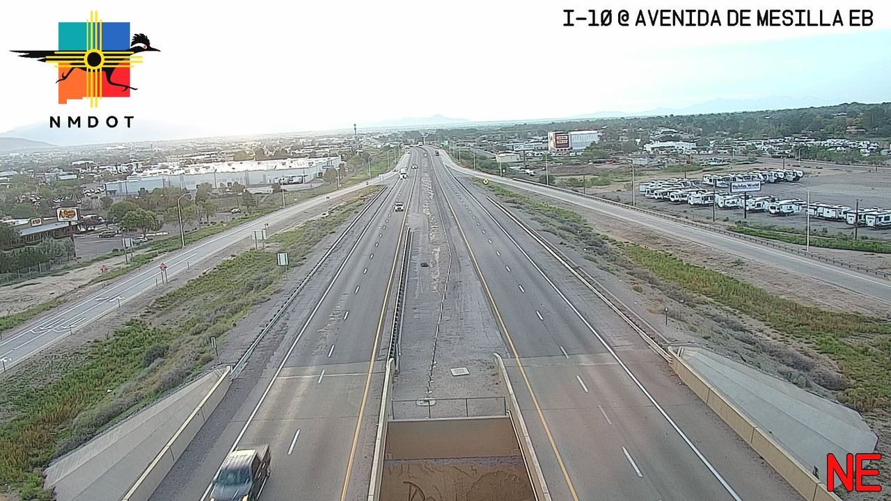 Highway I-10 at Avenida de Mesilla EB shows light traffic with a single vehicle approaching an overpass, while a large RV parking lot is visible to the right under clear skies.