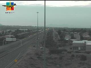 Multi-lane highway with moderate traffic flow under overcast skies, surrounded by desert vegetation and distant mountains.
