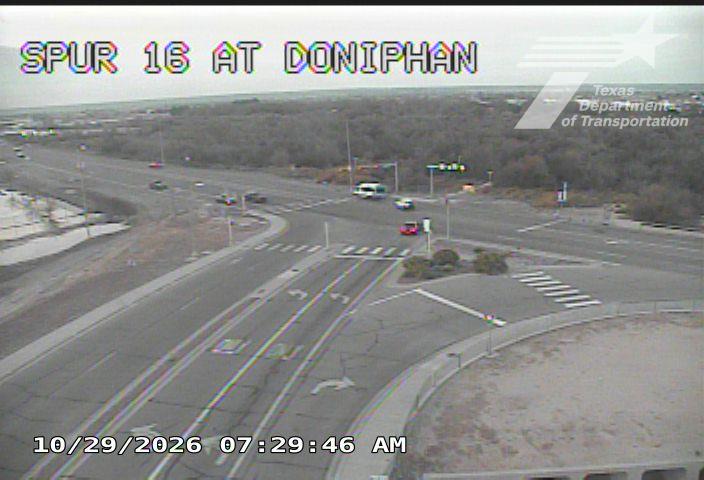 A wide view of a multi-lane intersection with light traffic, including a few cars and a white van, under overcast skies with no visible work zones or incidents.