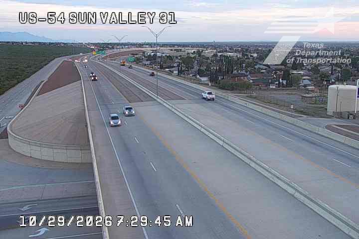 Light traffic flows on a multi-lane highway with vehicles moving in both directions under clear skies.