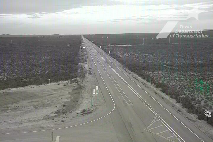 A wide, multi-lane highway stretches through an open, arid landscape with minimal traffic and no visible vehicles or work activity.